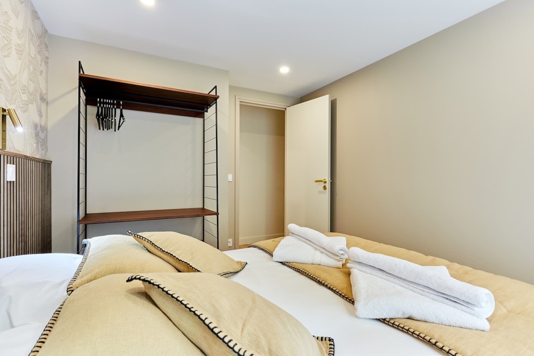 A hotel room with a bed, a wooden headboard, a wardrobe, and a mirror.