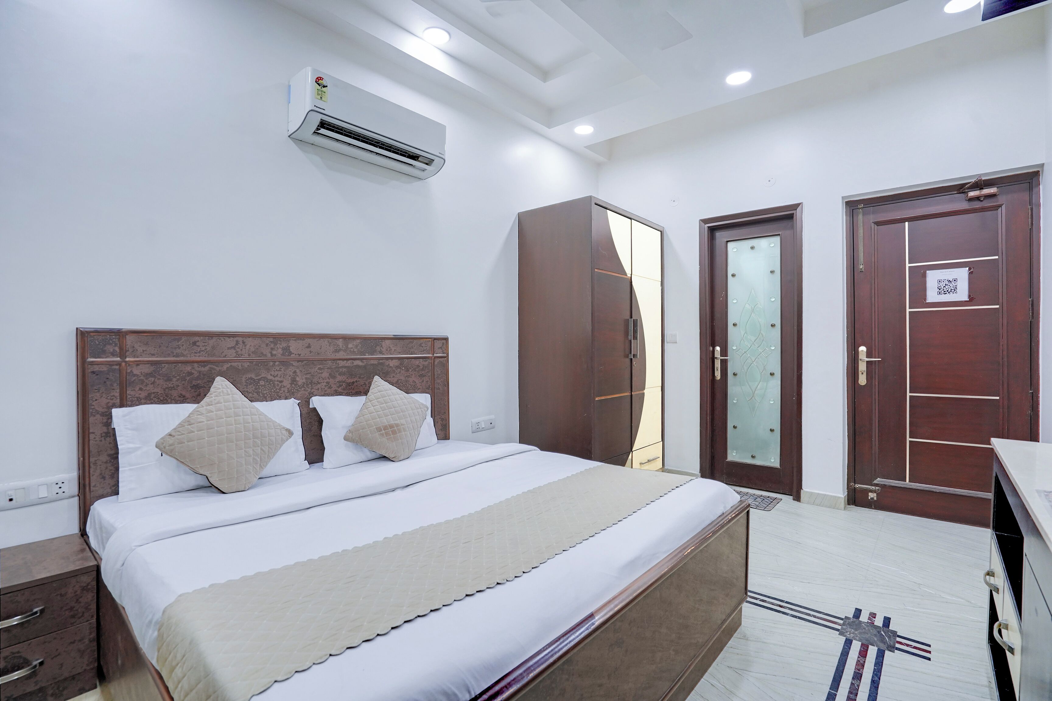 A hotel room with a bed, wardrobe, and two doors.
