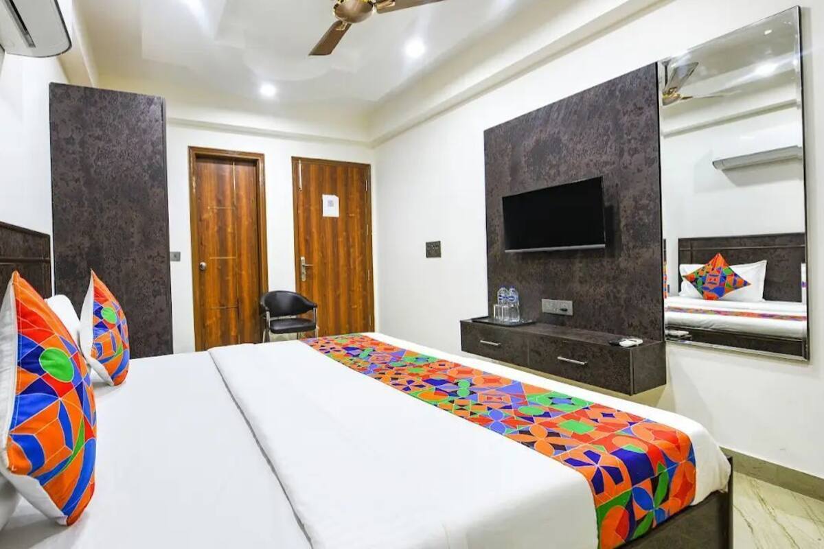 Een hotelkamer met een bed, een televisie, een kledingkast en een spiegel.