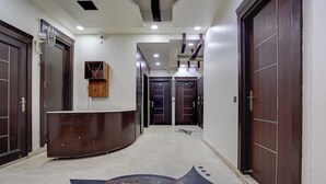 A hotel hallway with a reception desk, wooden doors, and a patterned floor. - Hotel Greysky Residency New Delhi (New Delhi)