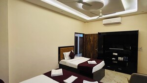 Une chambre d’hôtel avec deux lits, un ventilateur de plafond, un appareil de climatisation, un téléviseur à écran plat et un sol en marbre.