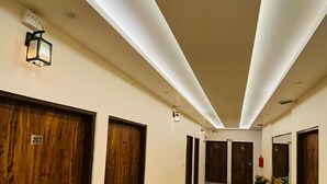 Un couloir d’hôtel avec des portes en bois, numérotées 207 et 208, et un sol en marbre.
