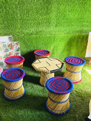 A set of woven stools with a central table, arranged on artificial grass. - Hotel DVL INN- Near Jalmahal Jaipur (Jaipur)