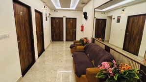 Un hall d’hôtel avec un sol en marbre, des portes en bois, un canapé et un miroir.