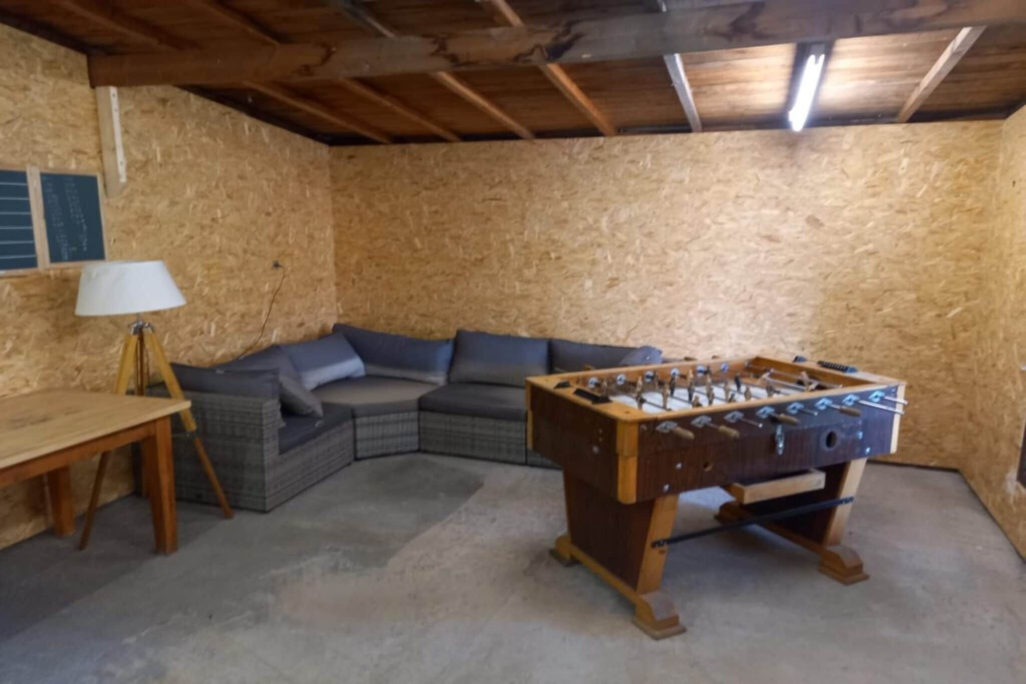 Una habitación acogedora con una mesa de fútbol, un sofá y una lámpara.