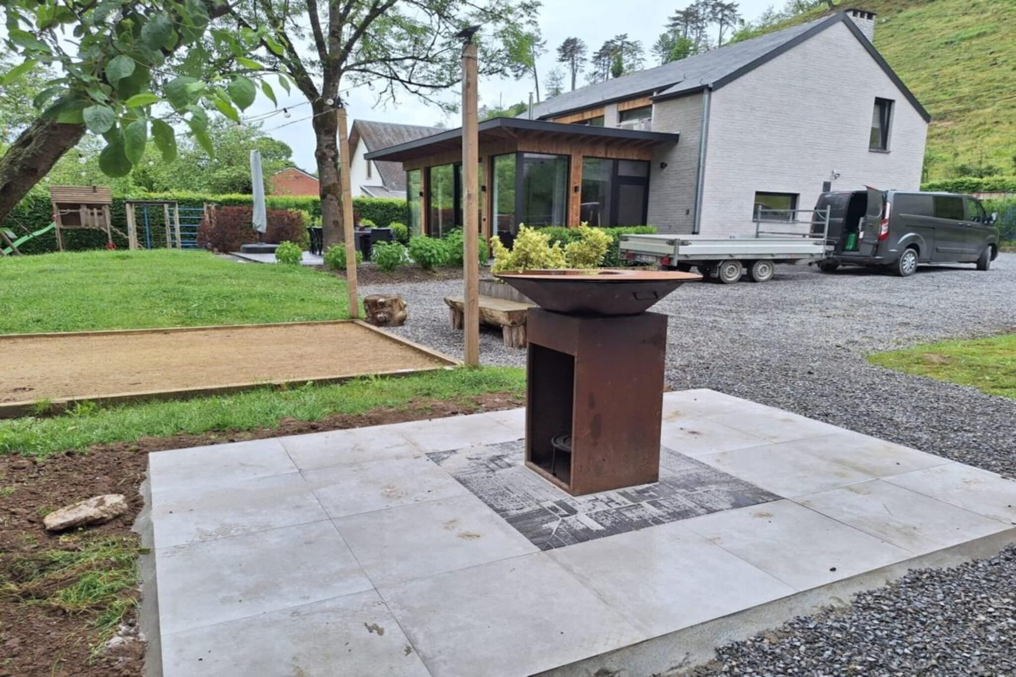 A modern house with a patio area featuring a fire pit and a gravel driveway.