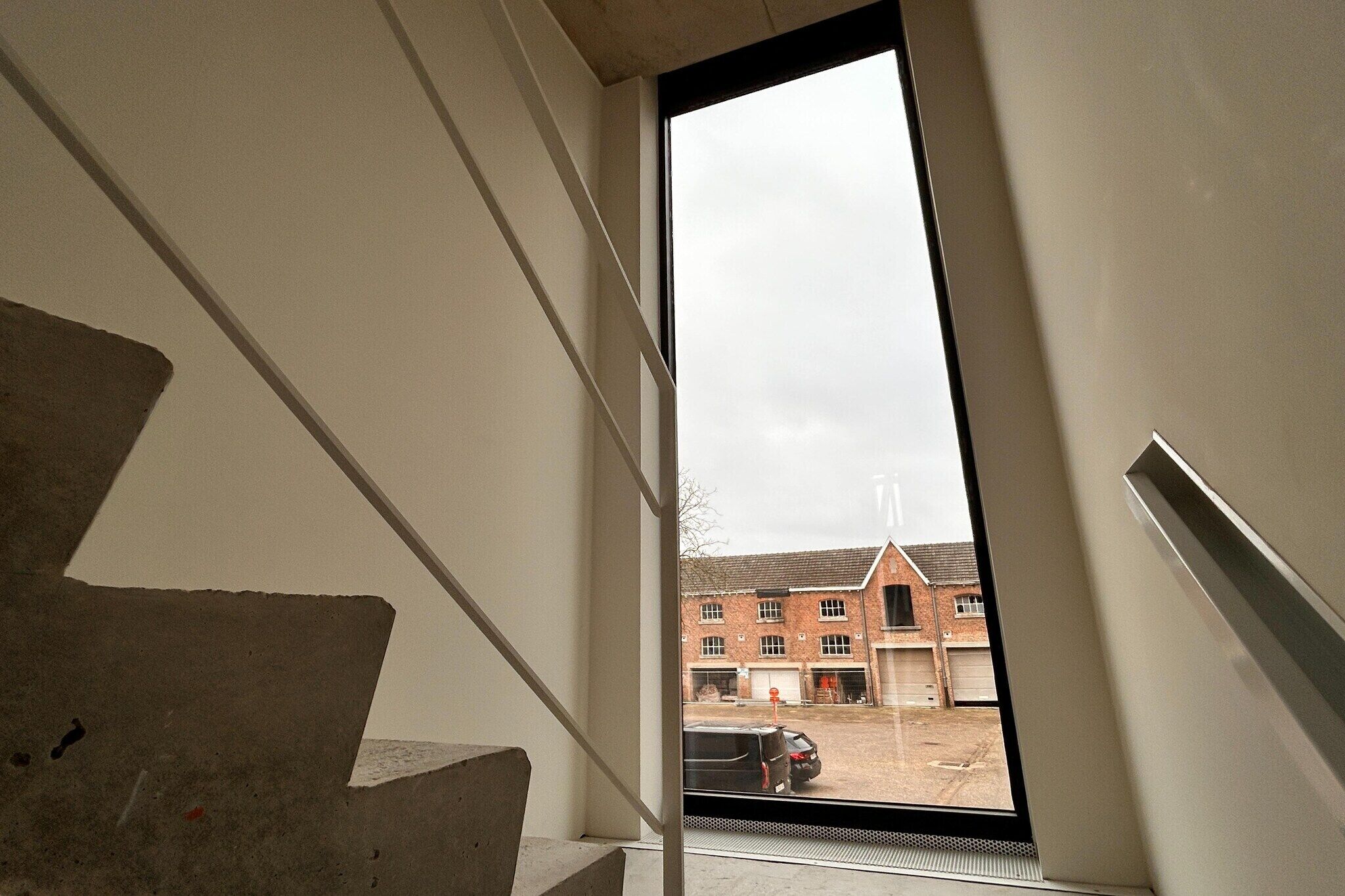 A view from a window overlooking a brick building with multiple garage doors.