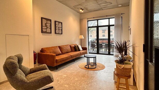 Un salon moderne avec un canapé, un fauteuil et une petite table.