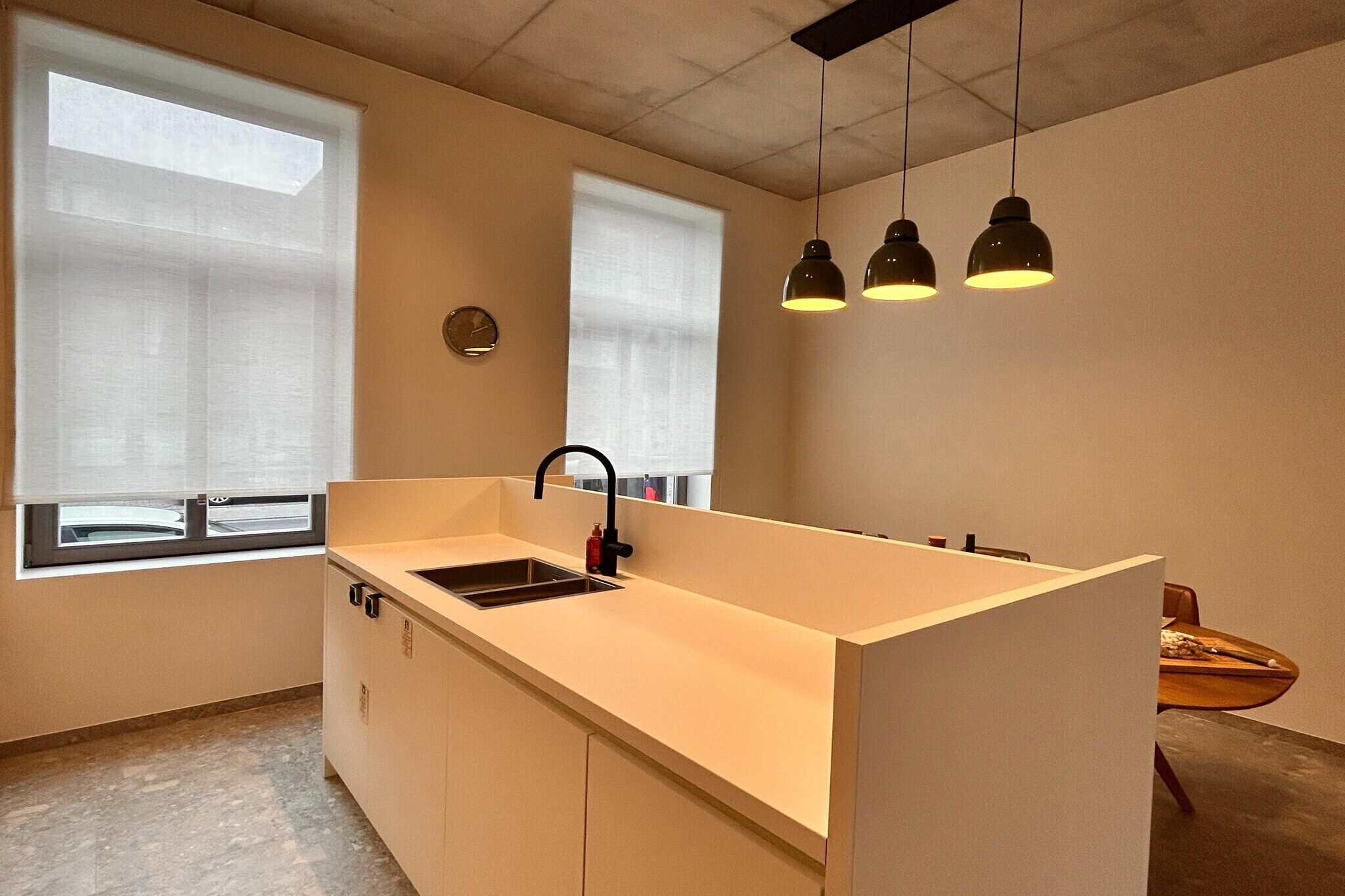A modern kitchen with a central island, a sink, and pendant lighting.