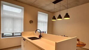 Une cuisine moderne dotée d’un îlot central, d’un évier et de luminaires suspendus.