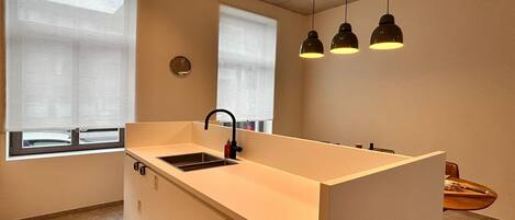 A modern kitchen with a central island, a sink, and pendant lighting.