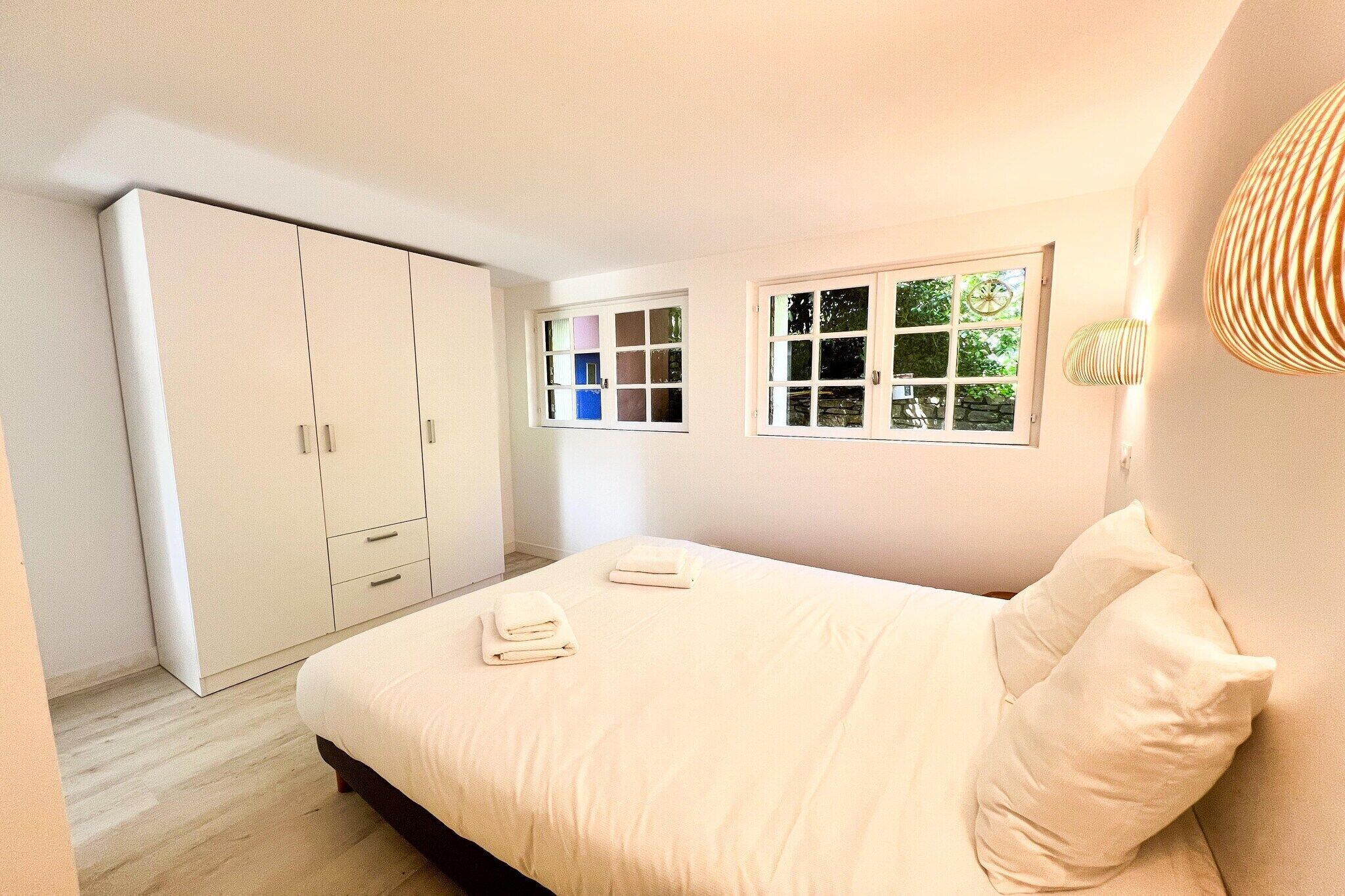 Un dormitorio con cama, armario y ventana.