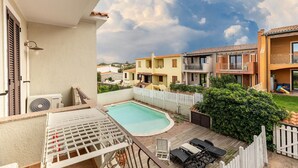 Un quartier résidentiel doté d’une piscine, d’une clôture en bois peinte en blanc et de maisons avec des balcons.