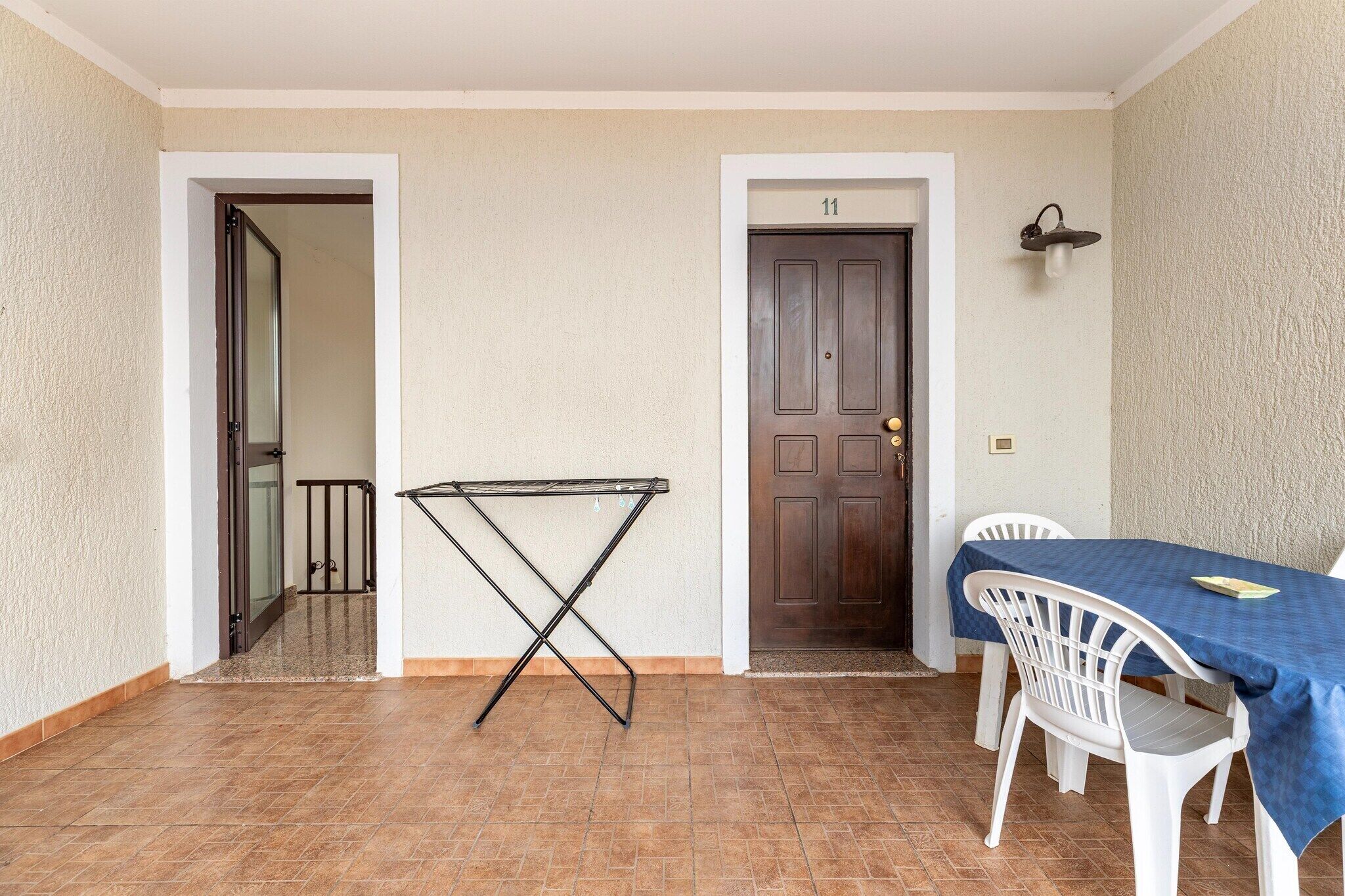 Une pièce comprenant une table à manger et des chaises, une porte portant le numéro 11, et une chaise pliante en métal.