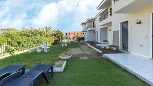 Ein modernes Gebäude mit gepflegtem Garten, Außenbestuhlung und freier Himmelssicht.