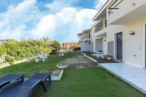 A modern building with a well-maintained garden, outdoor seating, and a clear view of the sky. - 150 meters from the sea, 2 swimming pools (Valledoria)