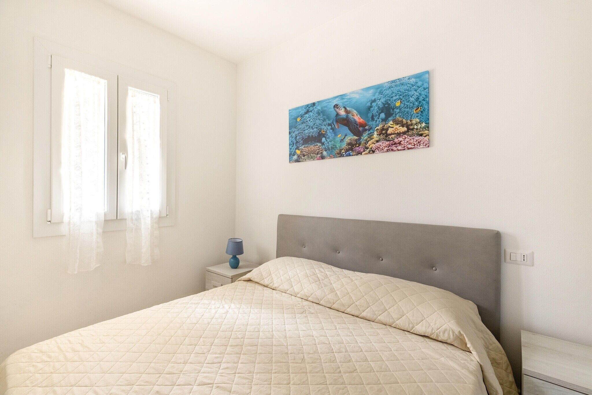 Une chambre à coucher avec un lit, une table de chevet, une lampe et un tableau au mur.