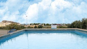 A swimming pool with a clear view of a distant hill and buildings. - Apartment in with swimming pool and sea view (Castelsardo)