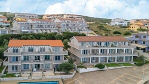 A multi-story residential building with a swimming pool and a parking area. - Apartment in with swimming pool and sea view (Castelsardo)