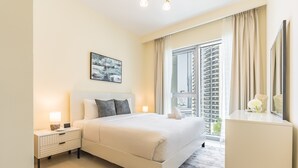Una camera da letto hotel moderna con un letto grande, comodini, un tavolo da notte, una cassettiera, una finestra con tende e un quadro appeso al muro.
