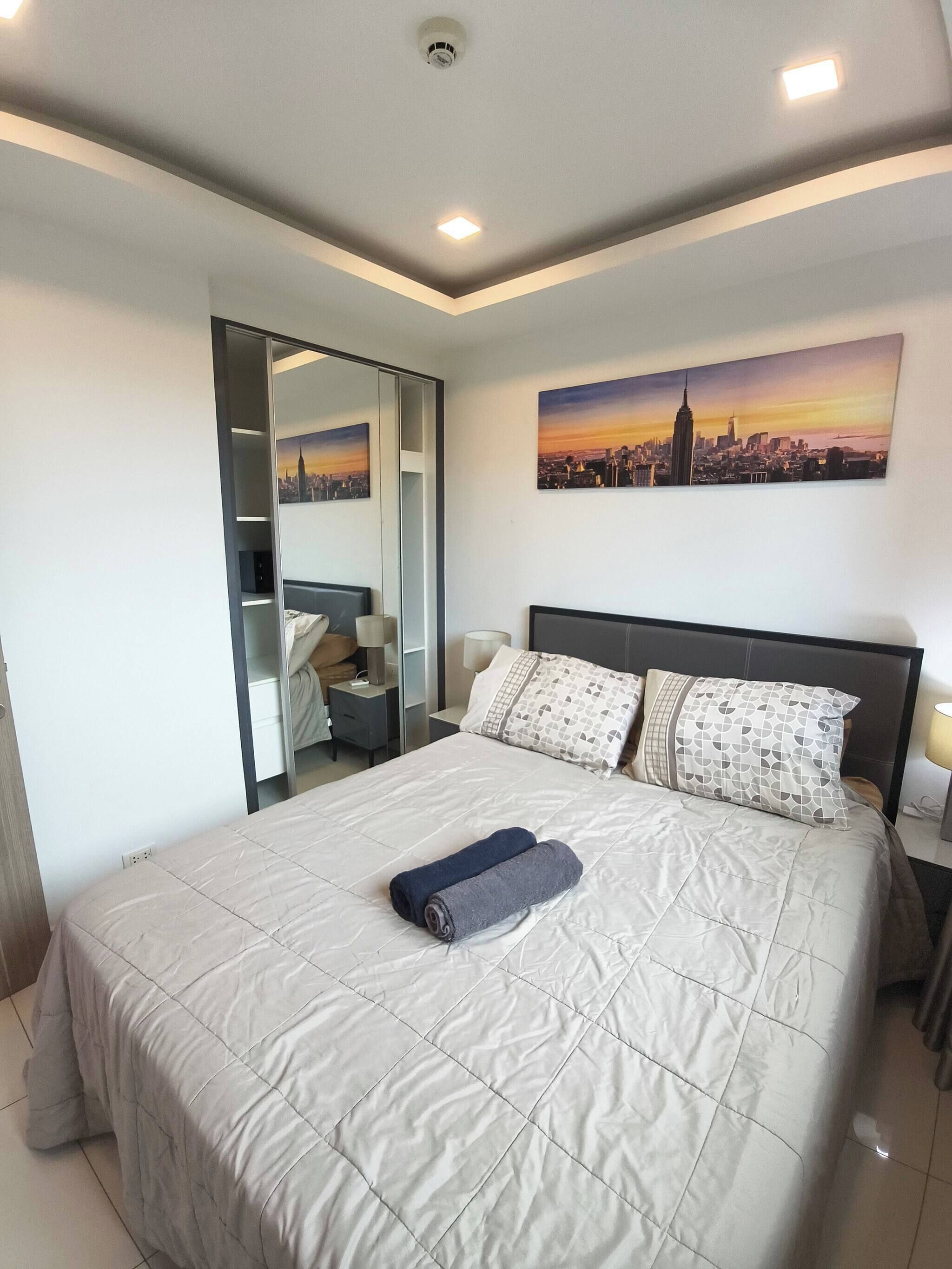 Un dormitorio moderno de hotel con una cama grande, un cuadro de un paisaje urbano y un vestidor.