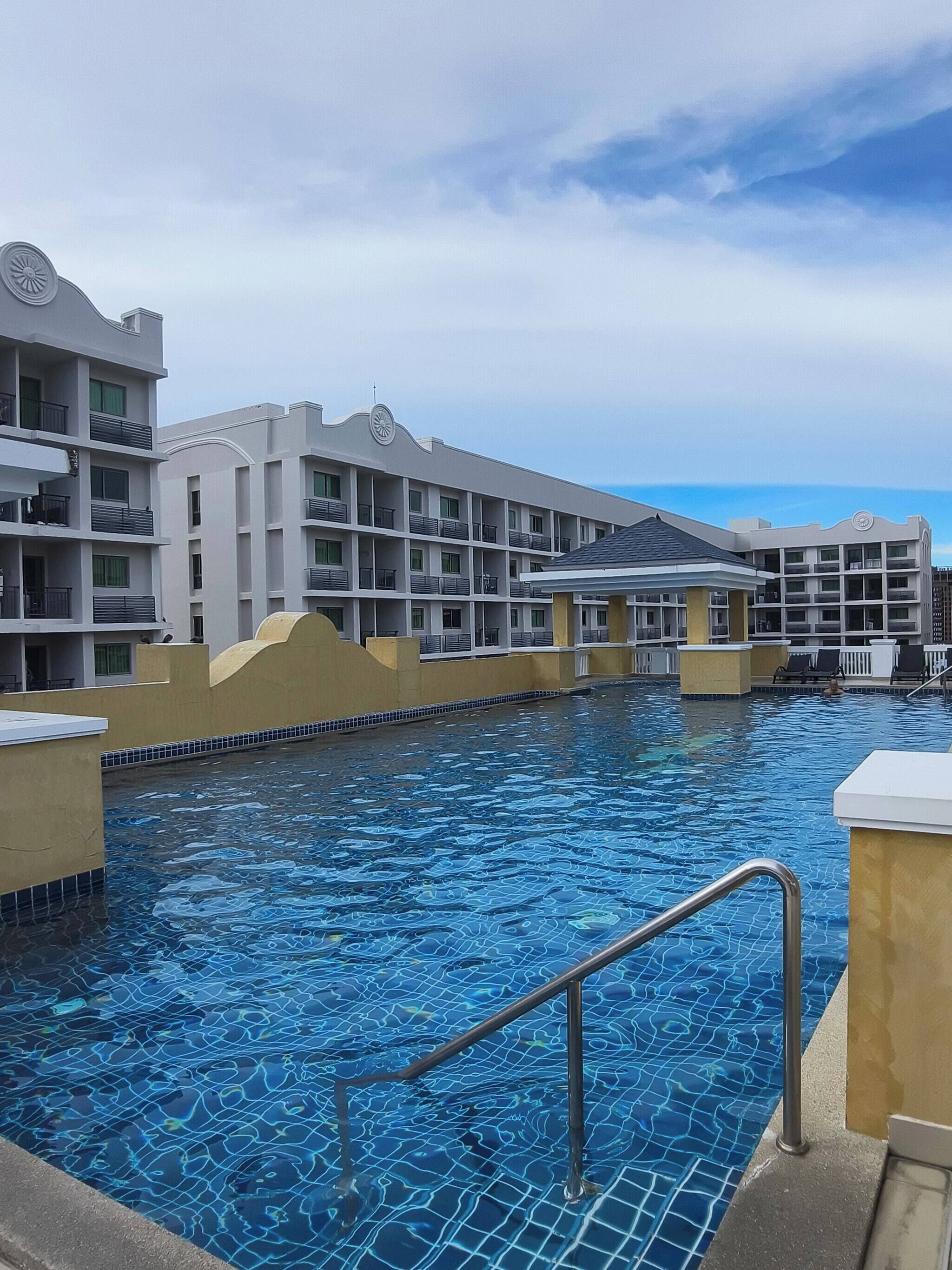 Ein Hotel mit Schwimmbad, mehreren Balkonen und einer überdachten Fläche.