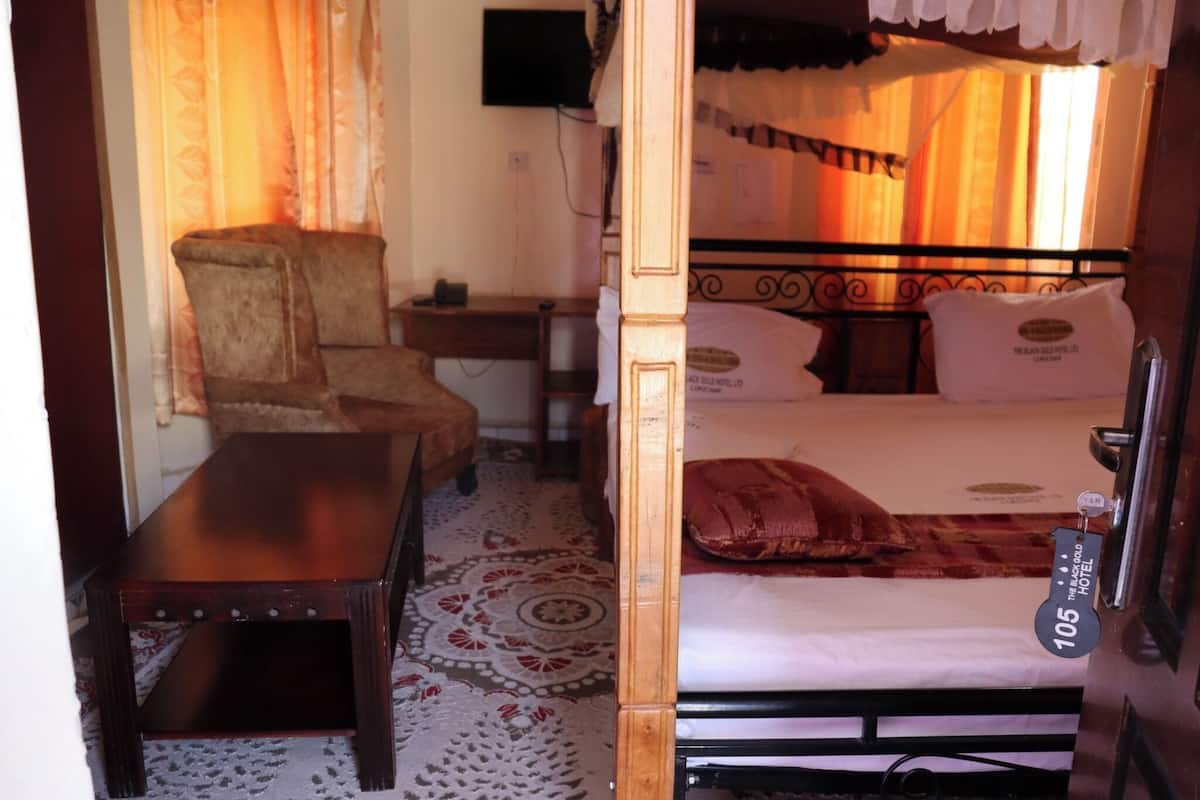 A room with a bed, a chair, a small table, and a carpeted floor.