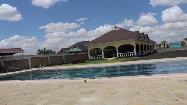 A swimming pool with a stone deck, a gazebo-like structure, and a clear sky. - The Black Gold Hotel Lokichar (Lokichar)