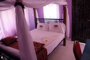 A bed with a canopy, a red chair, and a wooden door. - The Black Gold Hotel Lokichar (Lokichar)