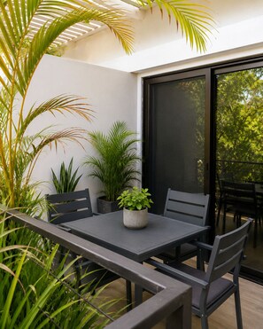 A modern outdoor dining area with a table and chairs, surrounded by potted plants and a large window. - 1 bedrooms - 2 bathrooms nice location (Provincia de Guanacaste)