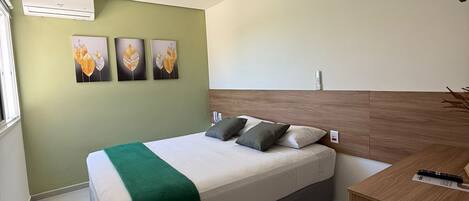Una habitación de hotel moderna con cama, escritorio y pared verde decorada con obras de arte.