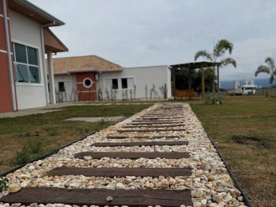 A pathway with wooden planks and pebbles leading to a building with a red and white facade.