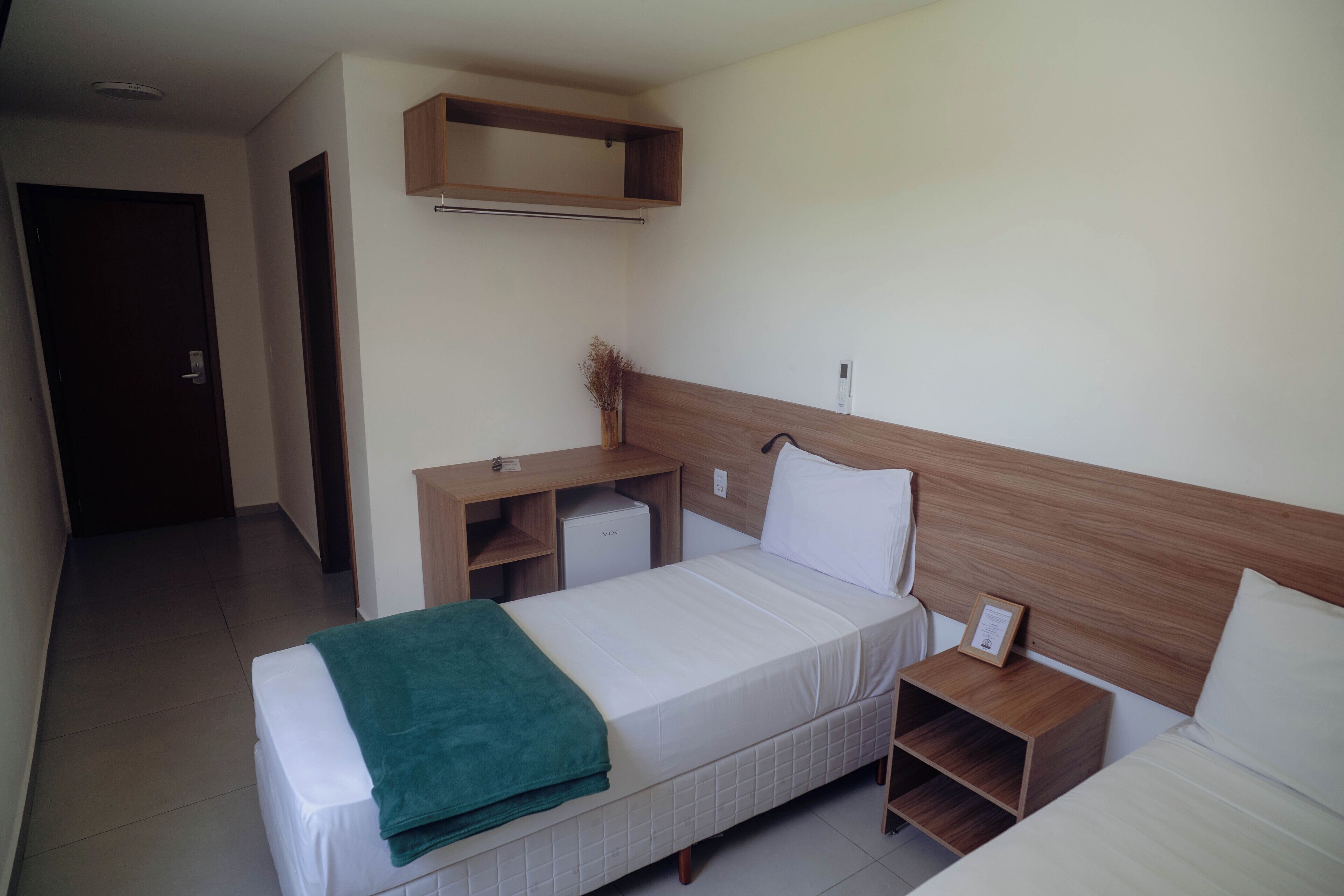 A hotel room with a bed, a bedside table, a desk, and a wardrobe.