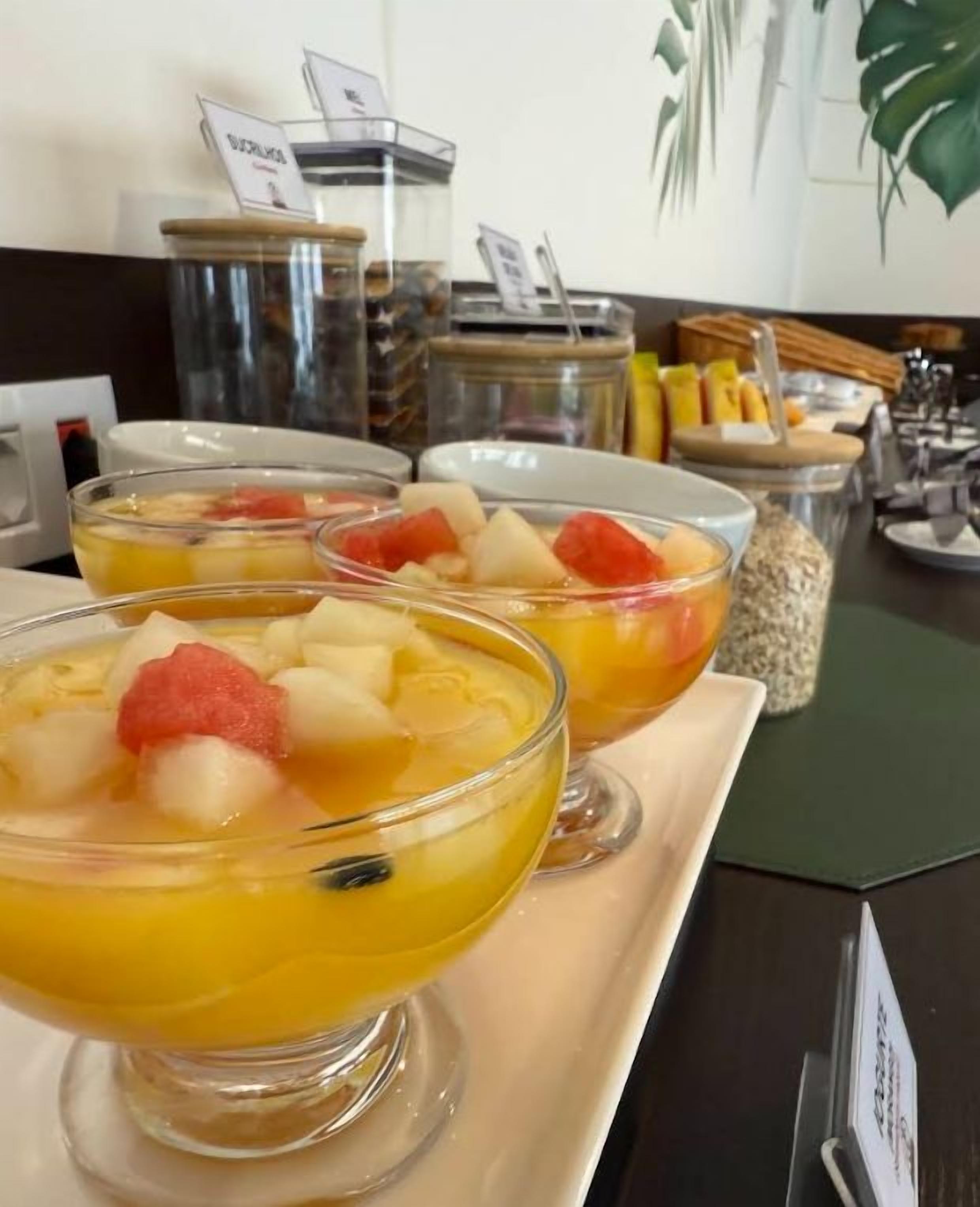 A breakfast buffet with fruit bowls and a variety of food items.