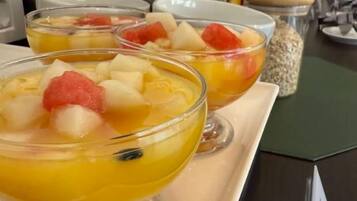 A breakfast buffet with fruit bowls and a variety of food items.