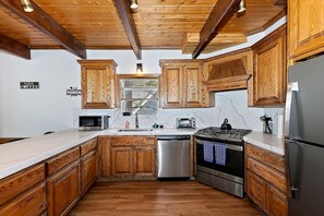 Eine Küche mit Holzausstattung, einem Edelstahl-Kühlschrank, einer Mikrowelle, einem Geschirrspüler und einem Herd.