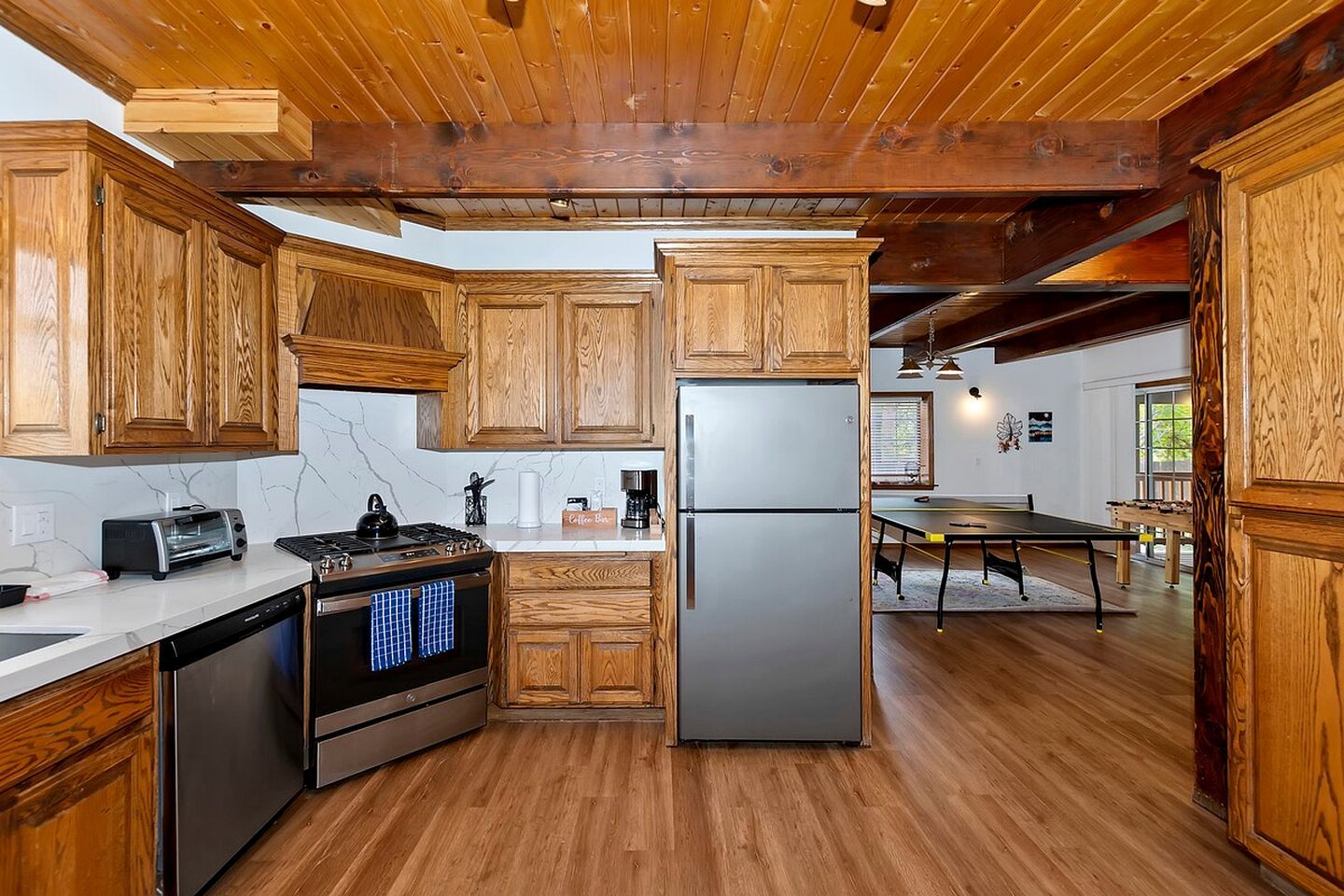A kitchen with wooden cabinets, a stainless steel refrigerator, a stove, and a coffee machine.