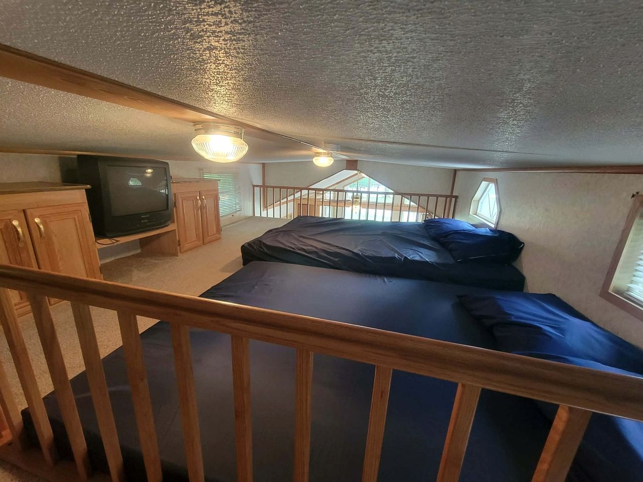 A compact bedroom with a bed, a television, and a small cabinet.