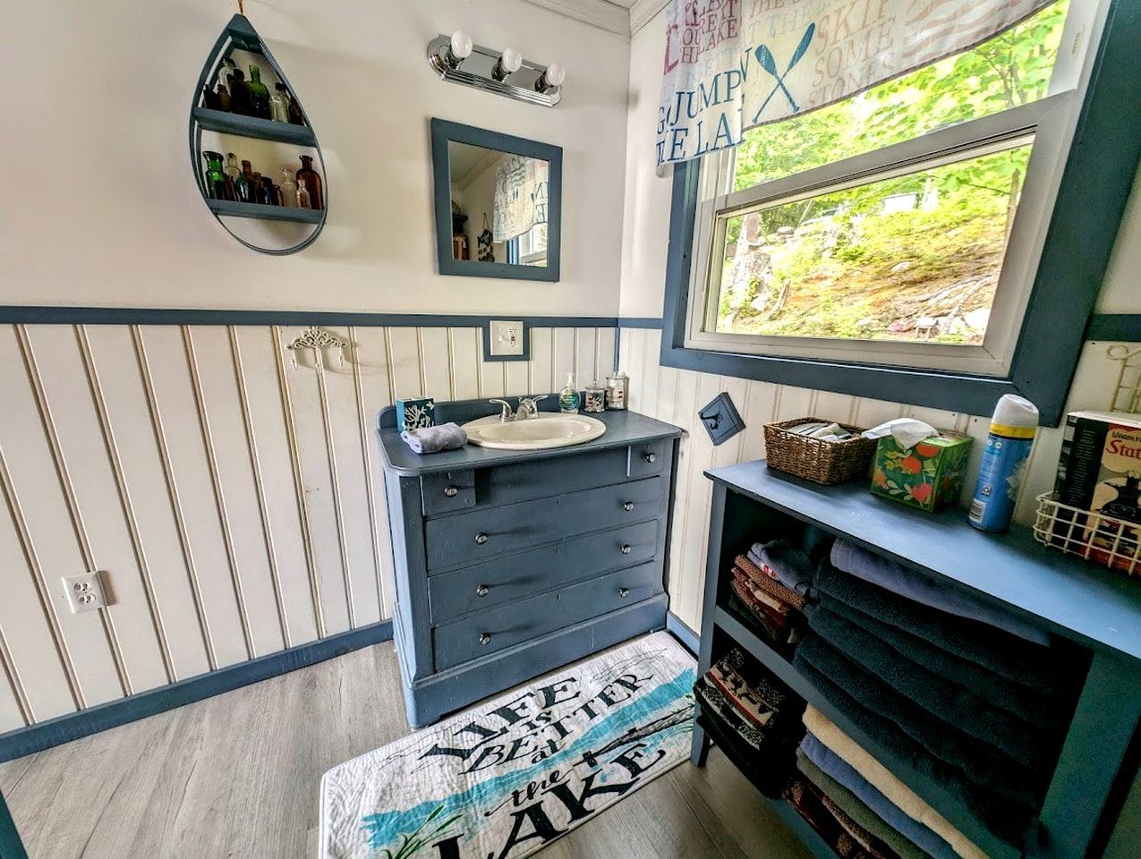 Une salle de bain avec un meuble-lavabo, un miroir, une fenêtre donnant sur un paysage agréable et un porte-serviettes.
