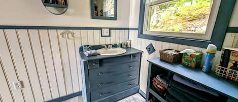 Une salle de bain avec un meuble-lavabo, un miroir, une fenêtre donnant sur un paysage agréable et un porte-serviettes.