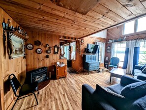 Ein gemütliches Blockhaus-Interieur mit Holzwänden, einem Kamin, einem Fernseher und einer komfortablen Sitzecke.