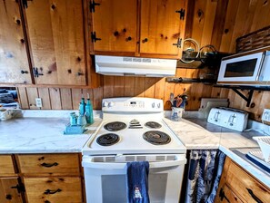 Una cocina funcional con armarios de madera, estufa blanca, microondas y tostadora.
