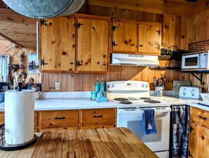 Une cuisine avec des meubles de rangement en bois, une cuisinière blanche, un four à micro-ondes et un grille-pain.