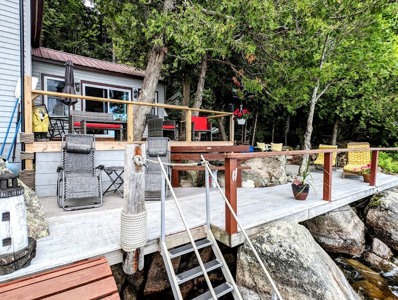 Eine Holzterrasse mit Gartenmöbeln, einer Leiter und einem Geländer.
