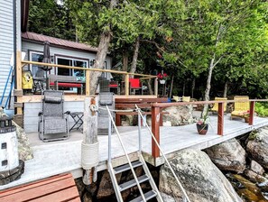 Eine Holzterrasse mit Gartenmöbeln, einer Leiter und einem Geländer.