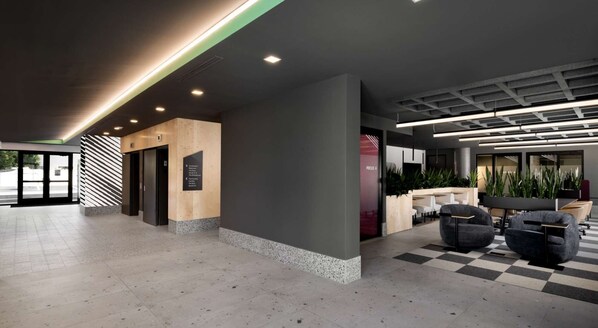 A modern lobby with a checkered floor, a reception desk, and a seating area with chairs.