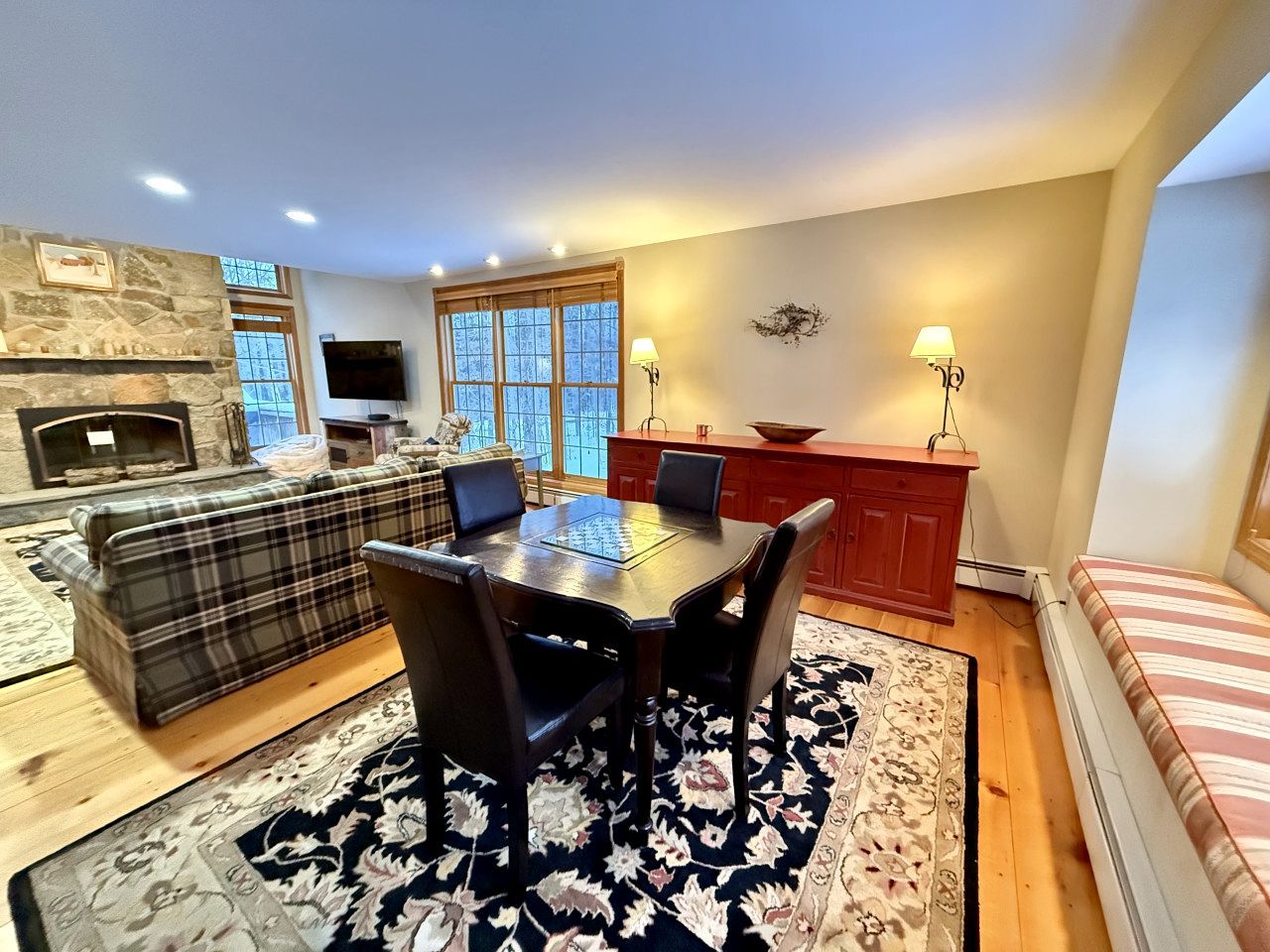 A living room with a fireplace, a dining area with a table and chairs, a sofa, and a television.