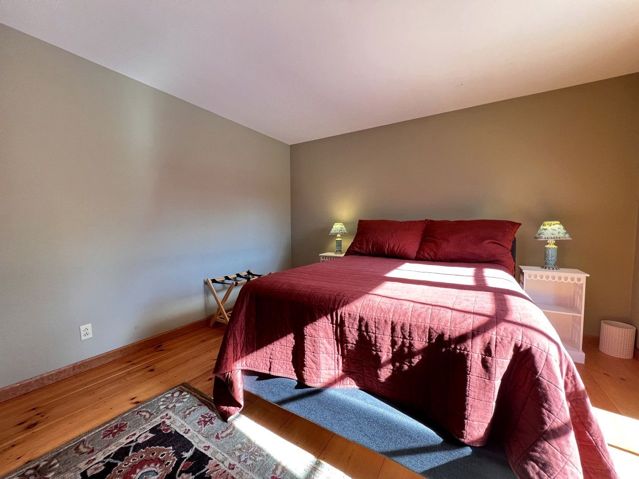 A bedroom with a bed, a nightstand, a lamp, and a rug.