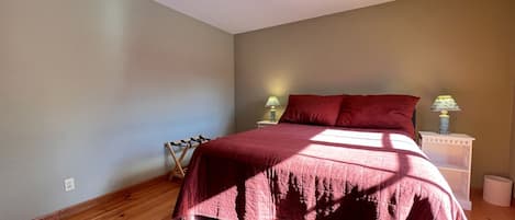 A bedroom with a bed, a nightstand, a lamp, and a rug.