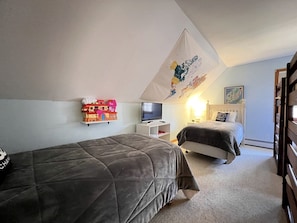 Ein Schlafzimmer mit zwei Betten, einem Fernseher, einer Karte an der Wand und einem Regal mit Spielzeug.